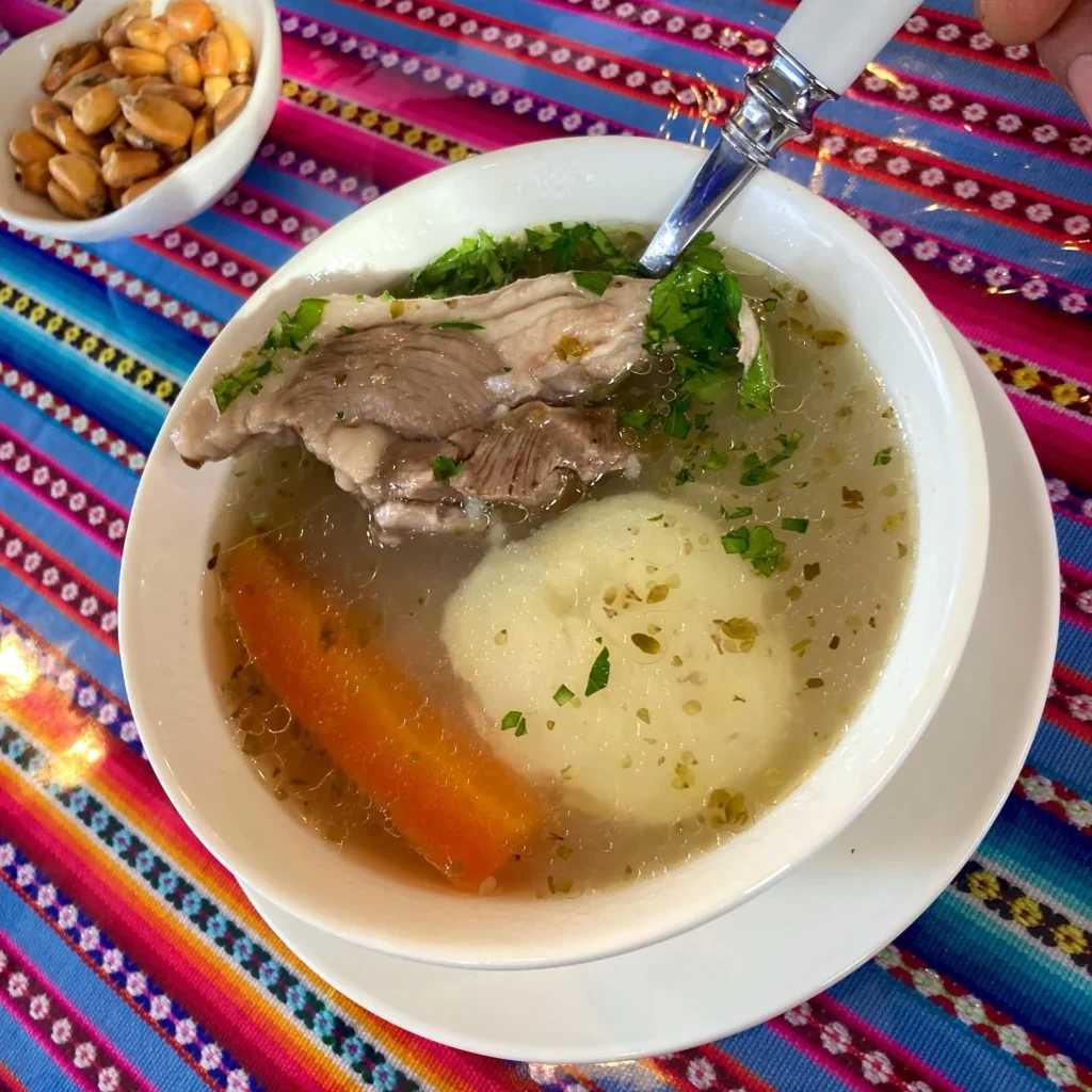 Caldo de Cordeiro, acompanhado de canchita, um prato típico da serra peruana