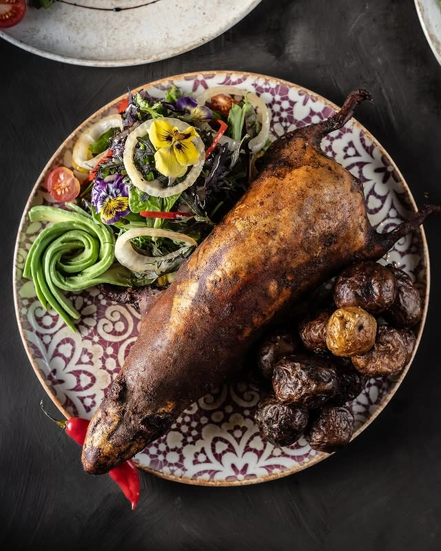 O prato tradicional "Cuy al Horno" acompanhado de salada e batatas assadas