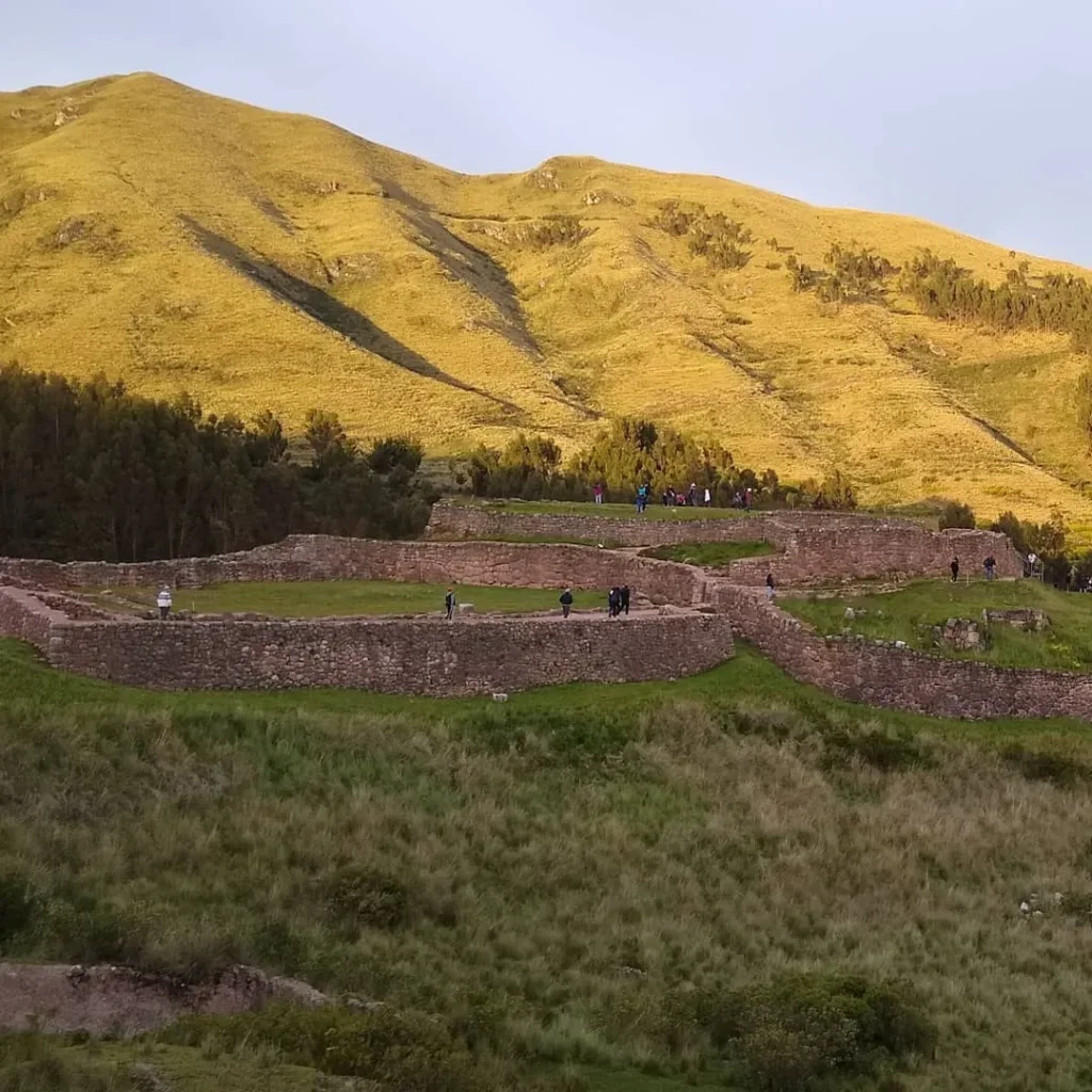 Tourists on the third level of the Puca Pucara Archaeological Complex, featuring defensive structures and small plazas.