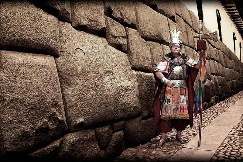Calle Hatun Rumiyoc con turistas observando la piedra de los 12 ángulos